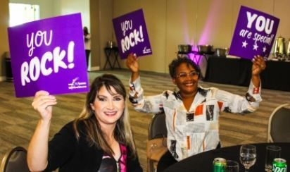 Two women are holding up purple signs that say `` you rock ''.