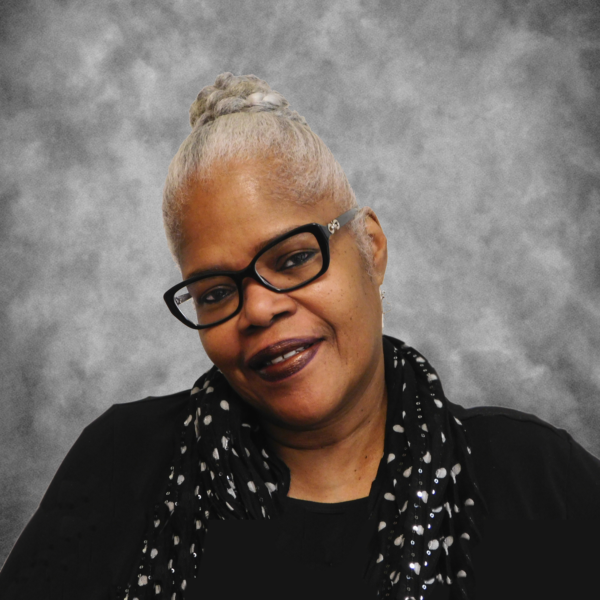 A woman wearing glasses and a plaid shirt smiles for the camera