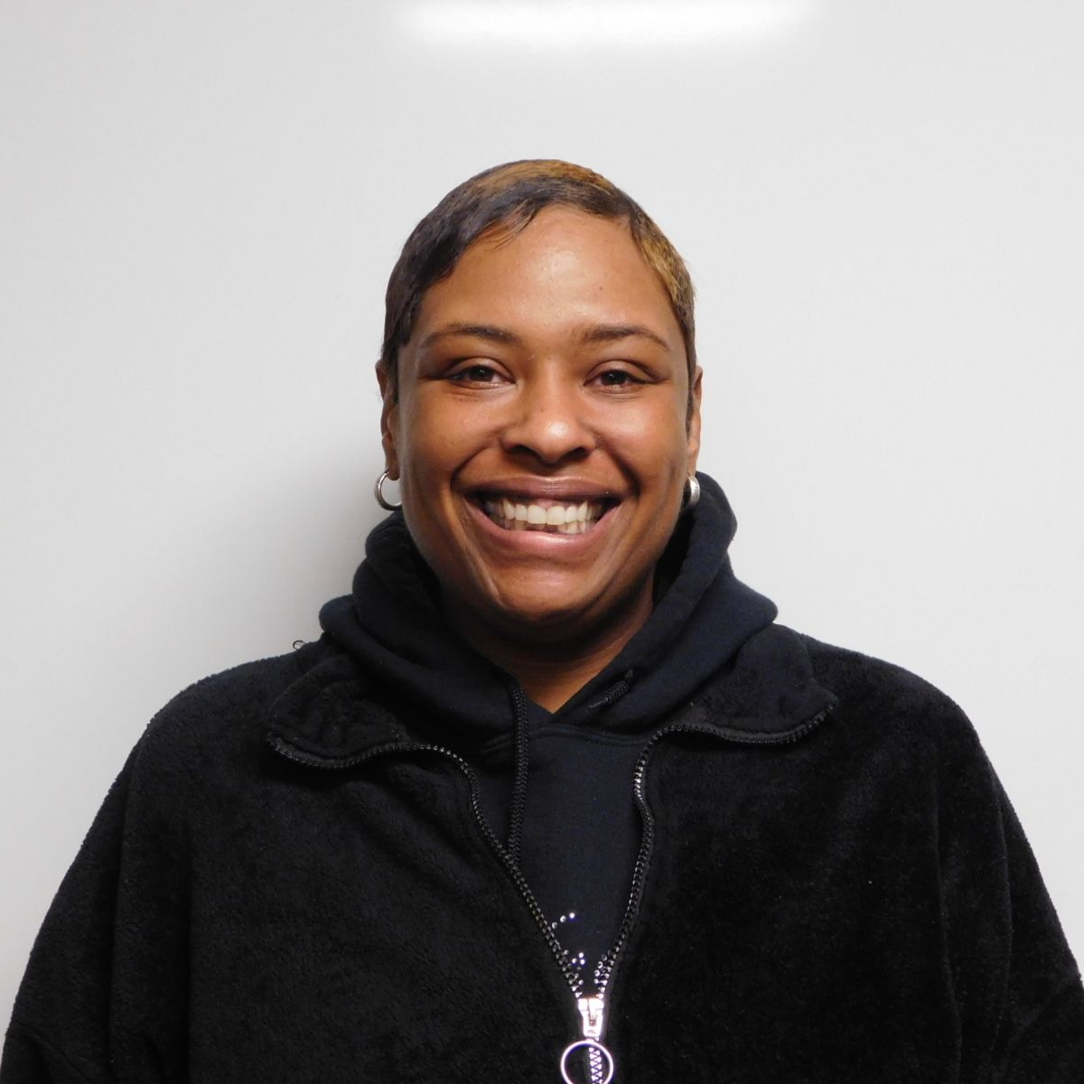 A woman wearing glasses and a scarf smiles for the camera