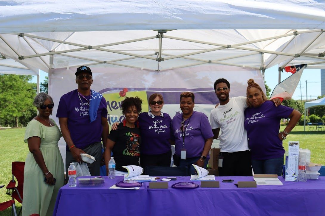 A group of people standing around a table under a tent.