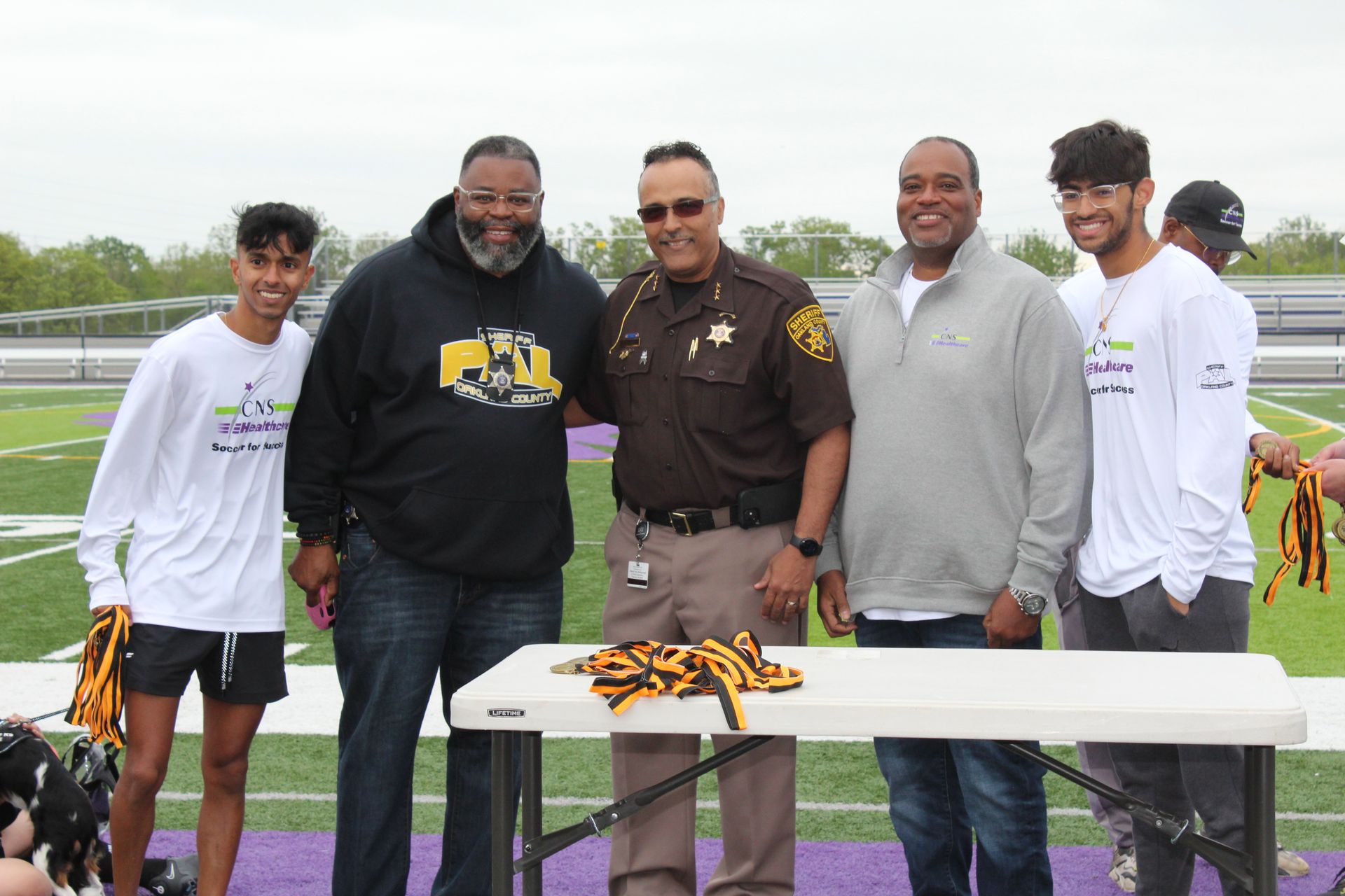A group of men are posing for a picture on a football field.