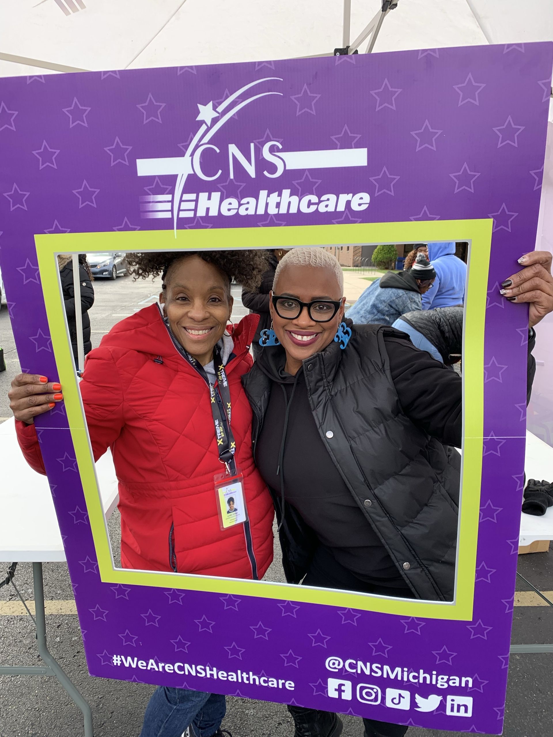 Two women are posing for a picture with a cns healthcare sign.
