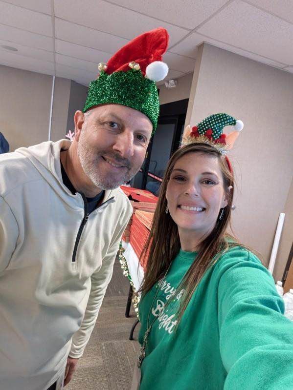 A man and a woman are posing for a selfie while wearing christmas hats.
