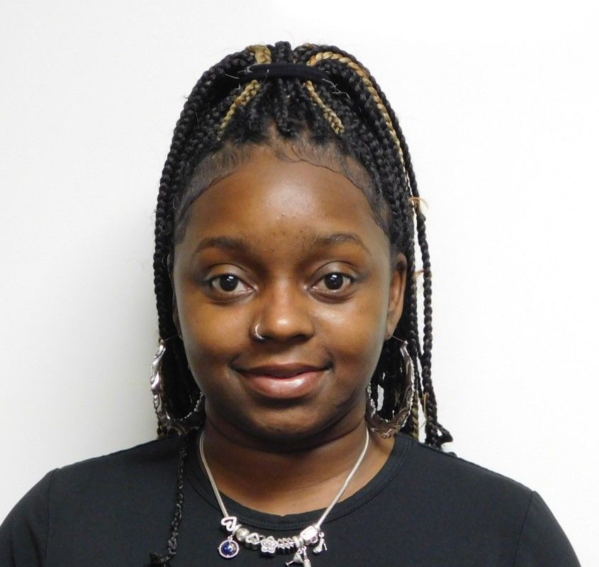 A woman wearing glasses and a bun looks at the camera