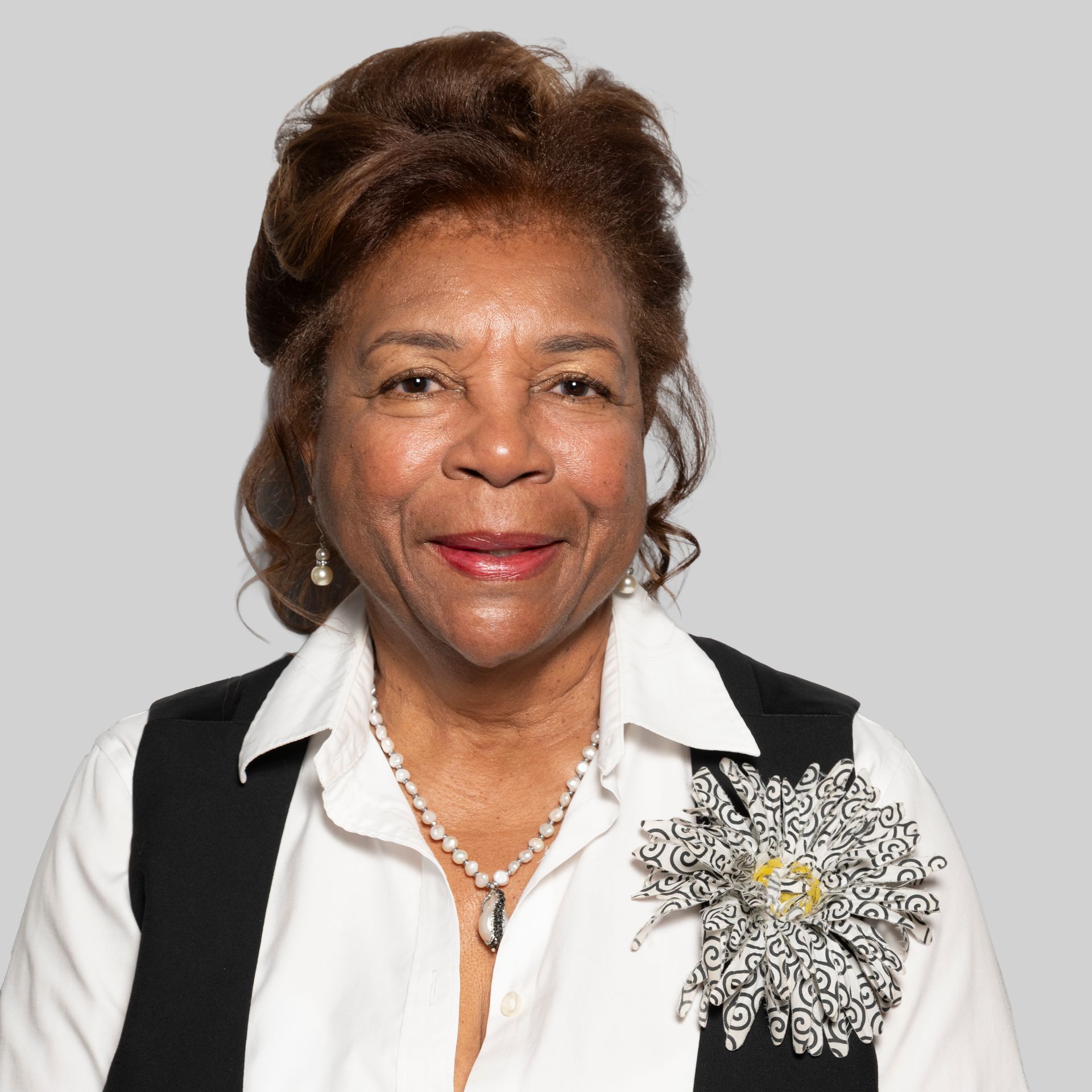 A woman wearing a necklace and earrings smiles for the camera