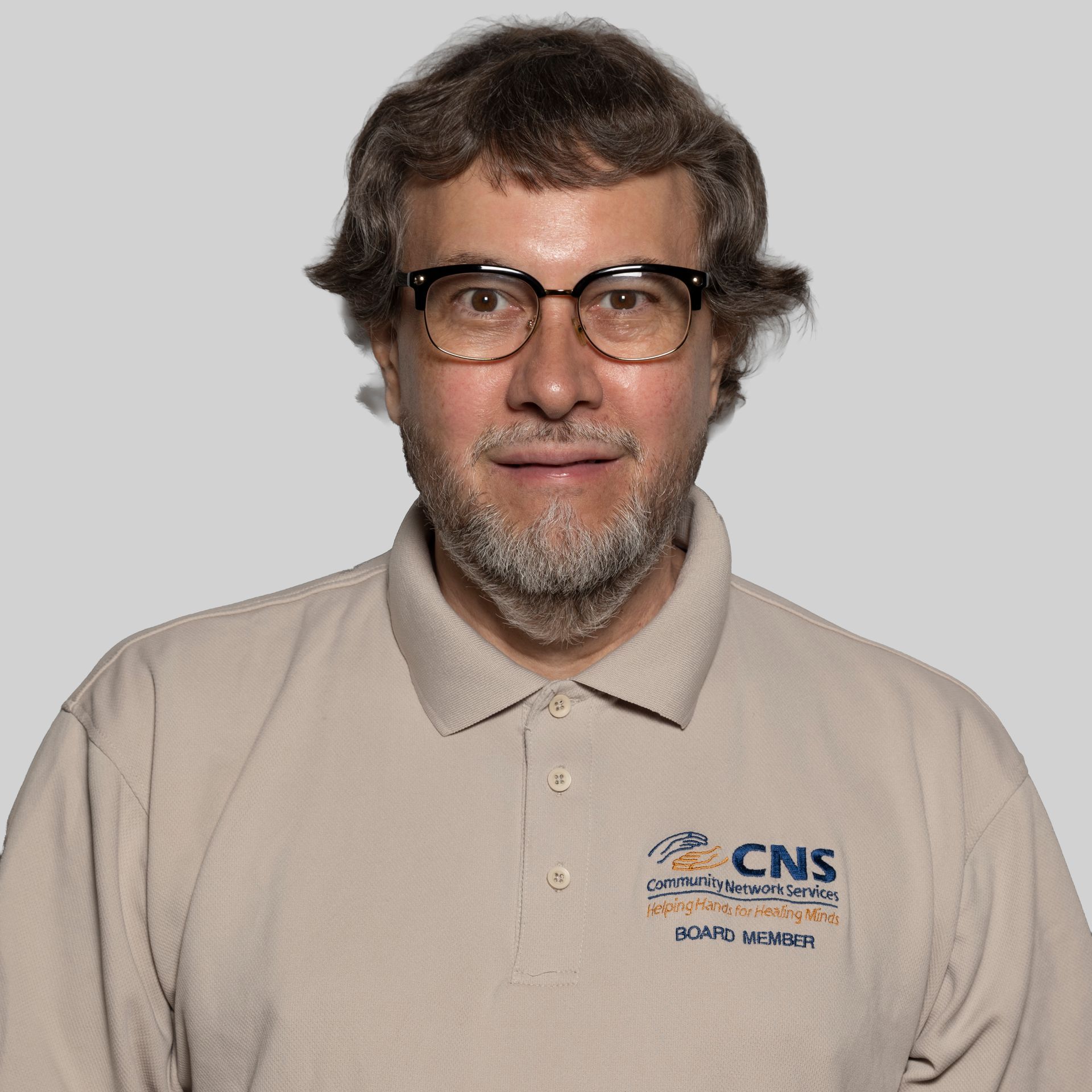 A man wearing a cns healthcare shirt smiles for the camera