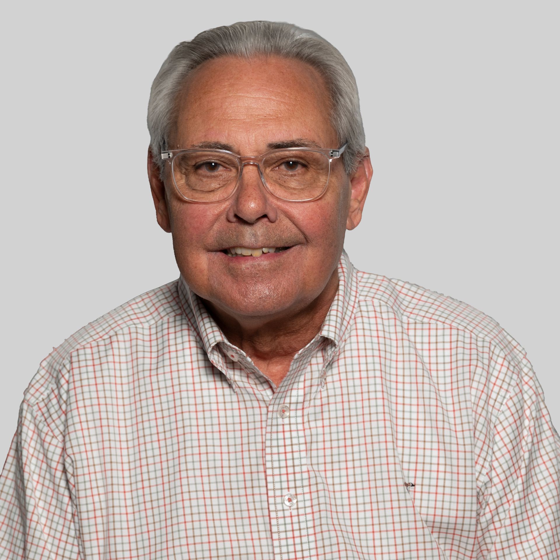 A man wearing glasses and a plaid shirt smiles for the camera