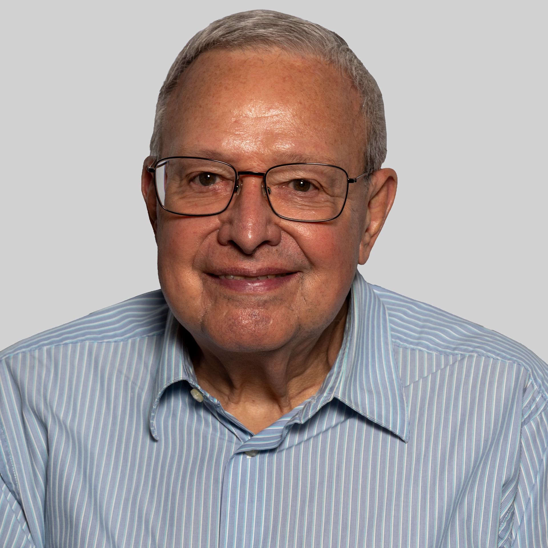 A man wearing glasses and a white shirt smiles for the camera