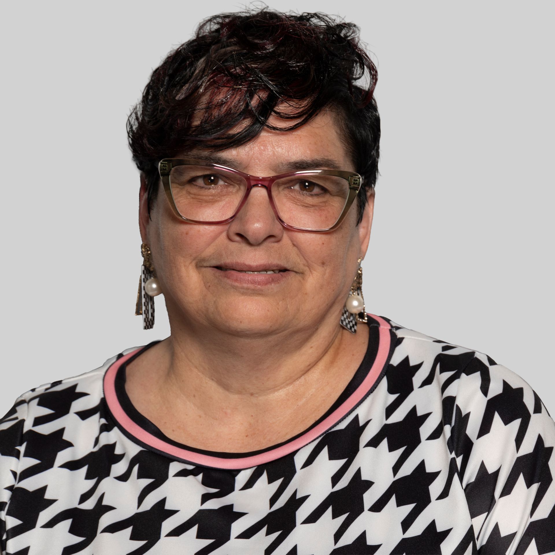 A woman with red hair and glasses is smiling for the camera