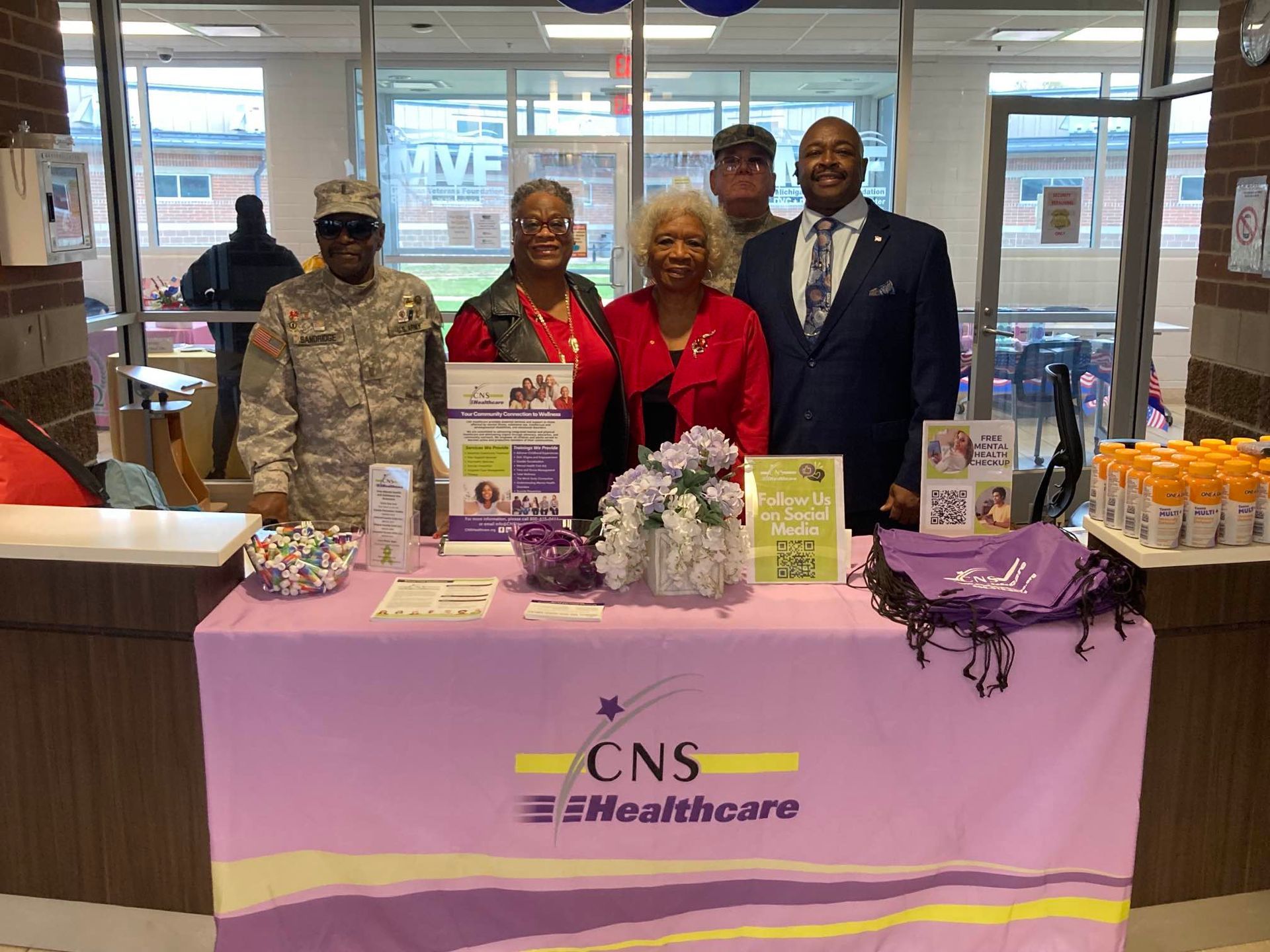 A group of people are standing around a purple table.