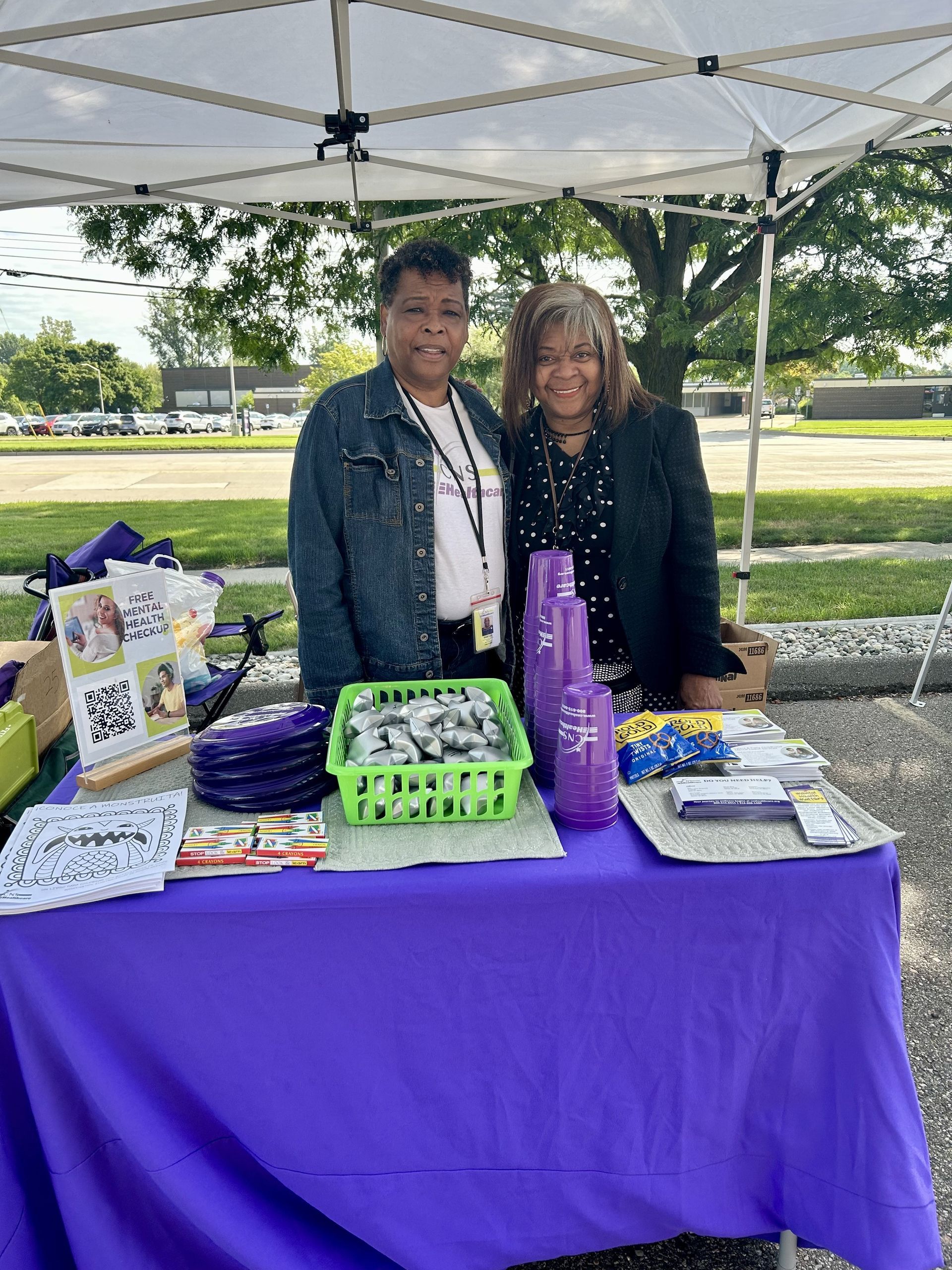 Two women are standing at a table under a tent.