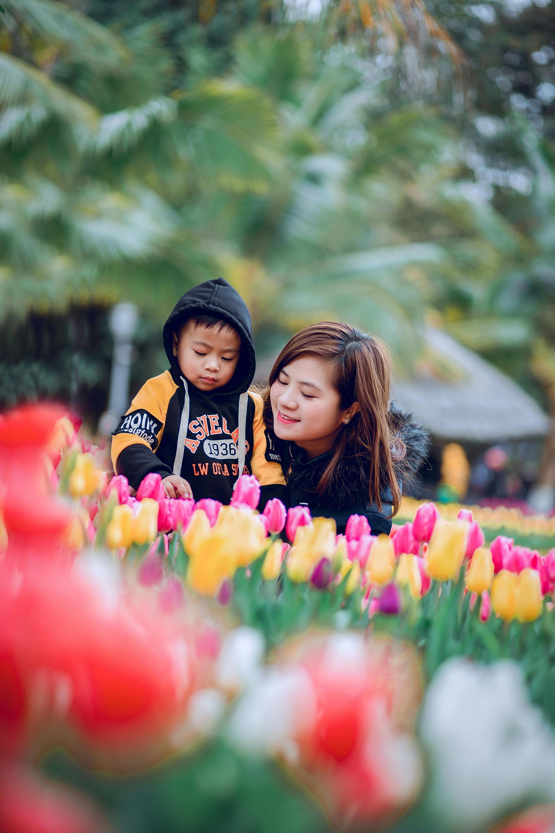 A woman and a child are sitting in a field of flowers.