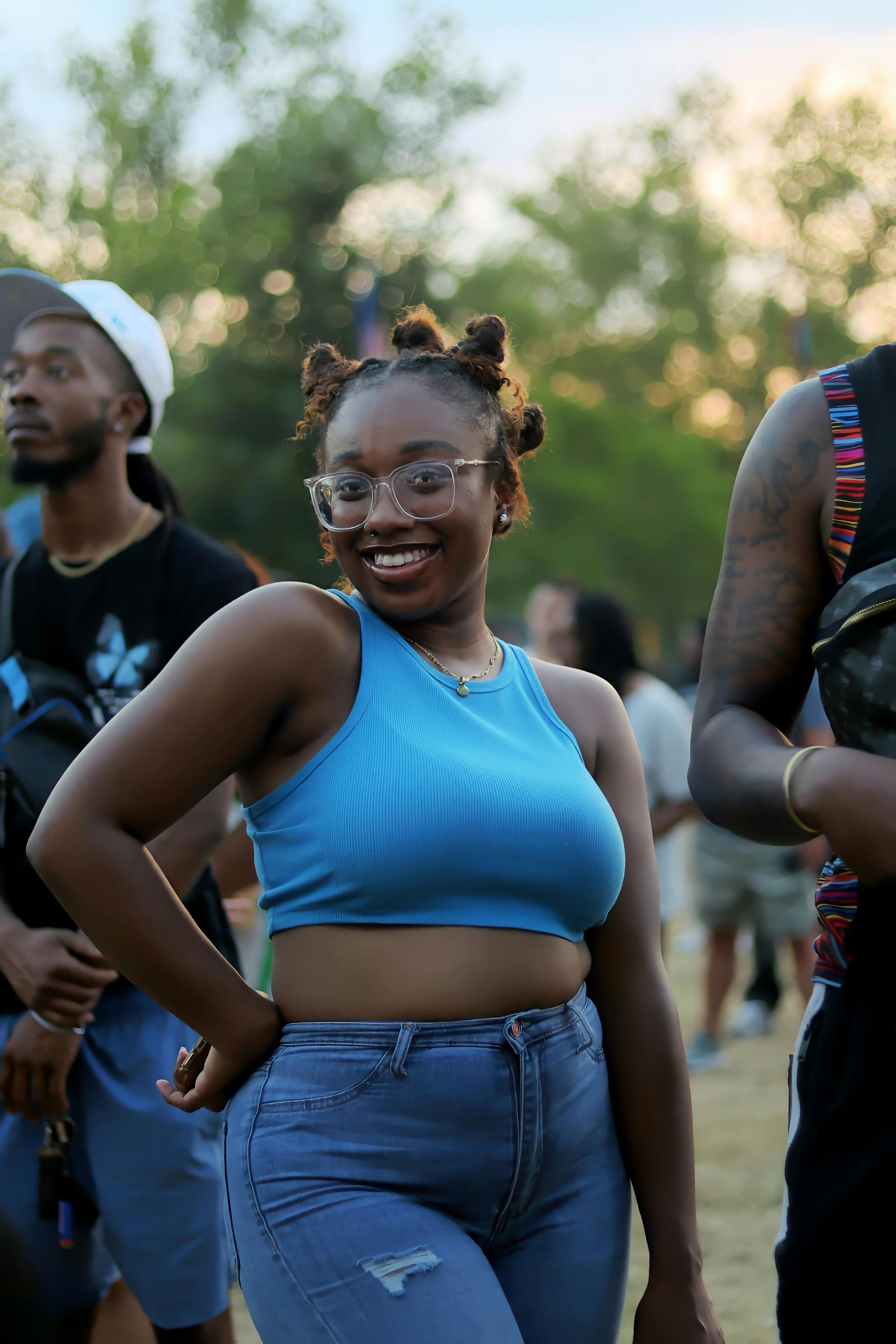 A woman in a blue crop top and jeans is standing in a crowd of people.