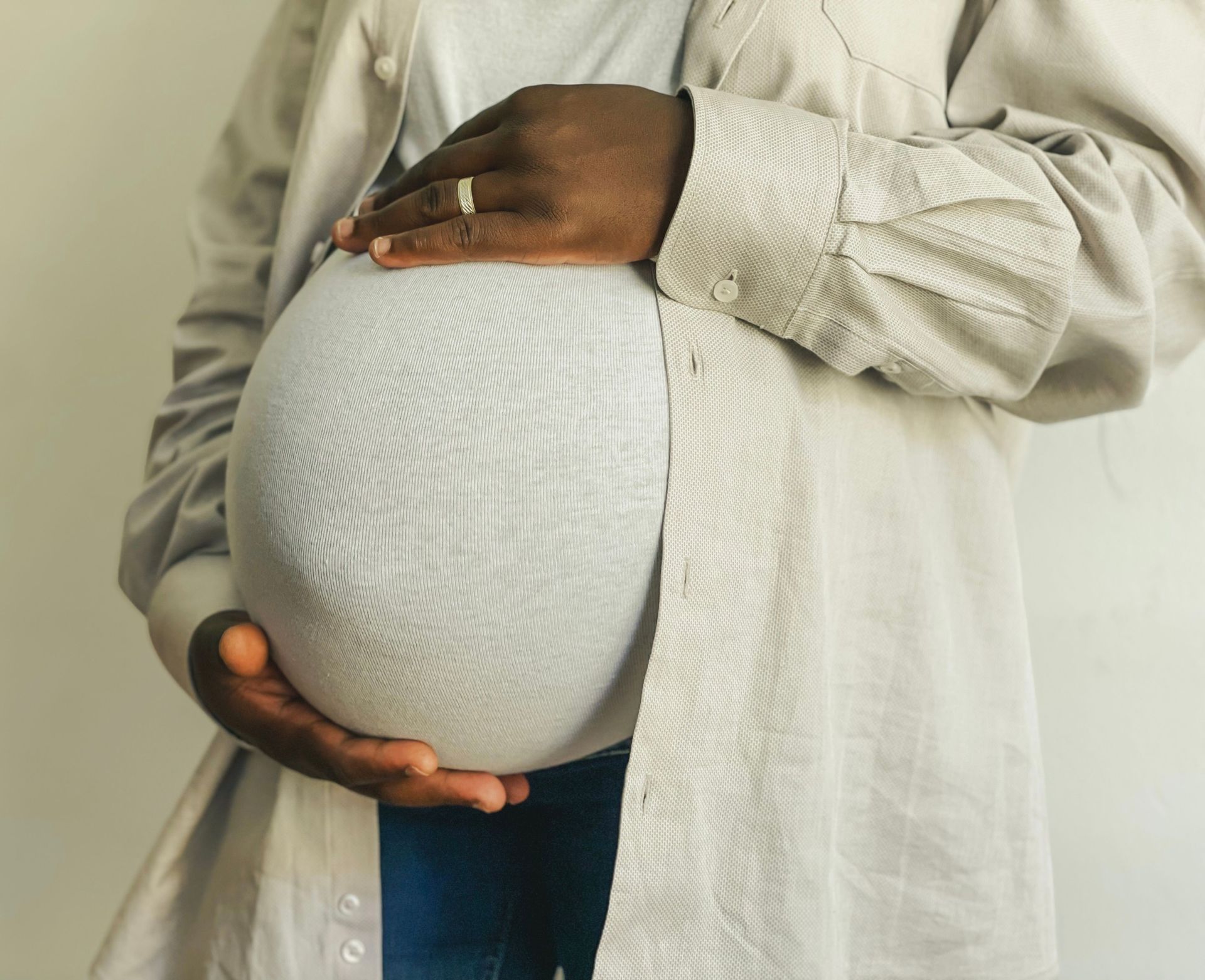 Pregnant woman holding her stomach against a light background