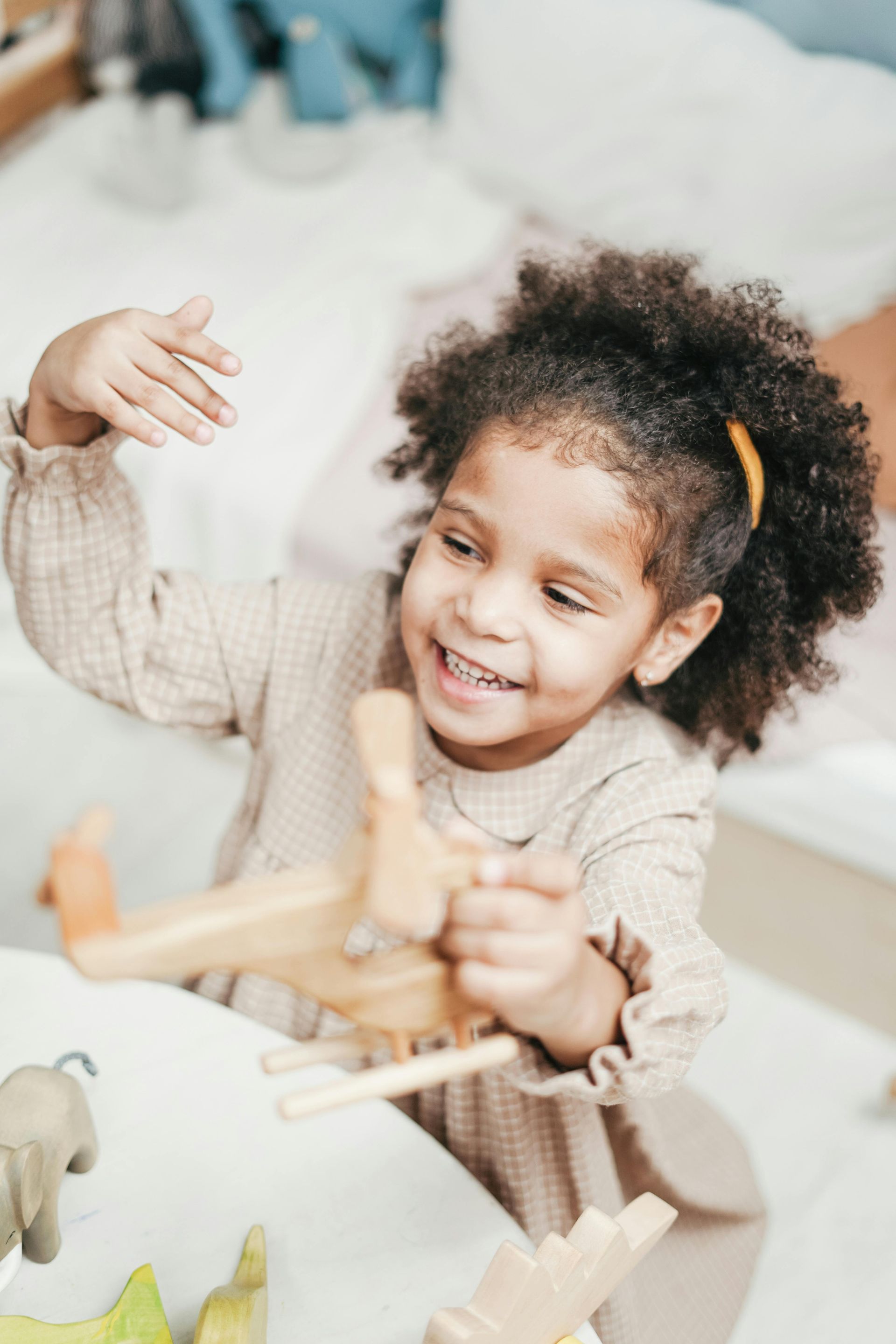 A little girl is sitting at a table playing with wooden toys.