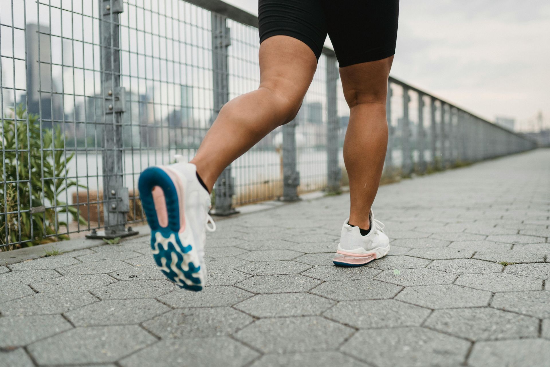 A person runs outside alongside a fence.