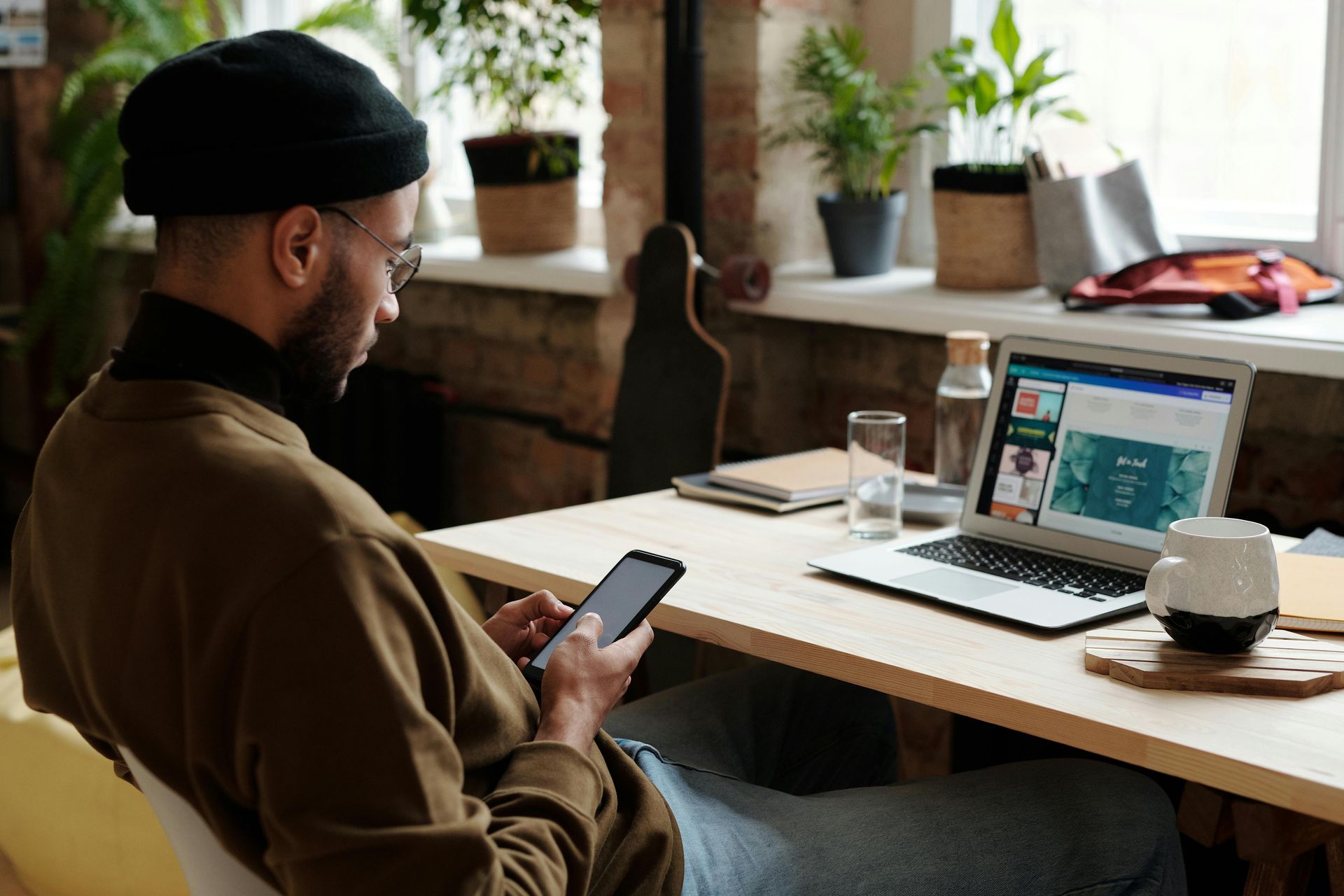 A man looks at his phone while sitting at his desk.