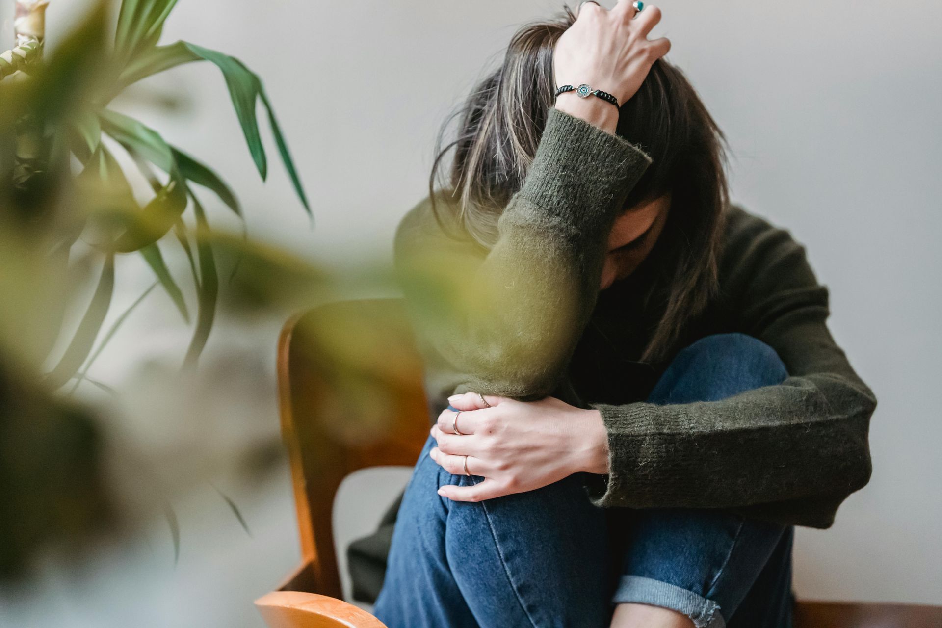 Teen sitting, head in hands, slumped in chair, indoors.