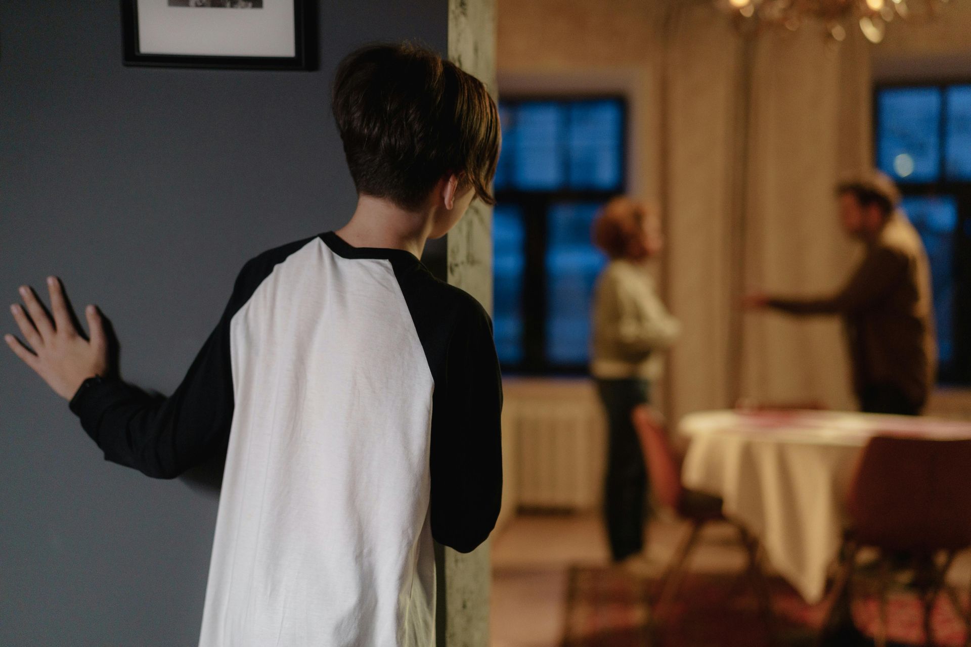 Boy watching as two adults argue in a dining room.