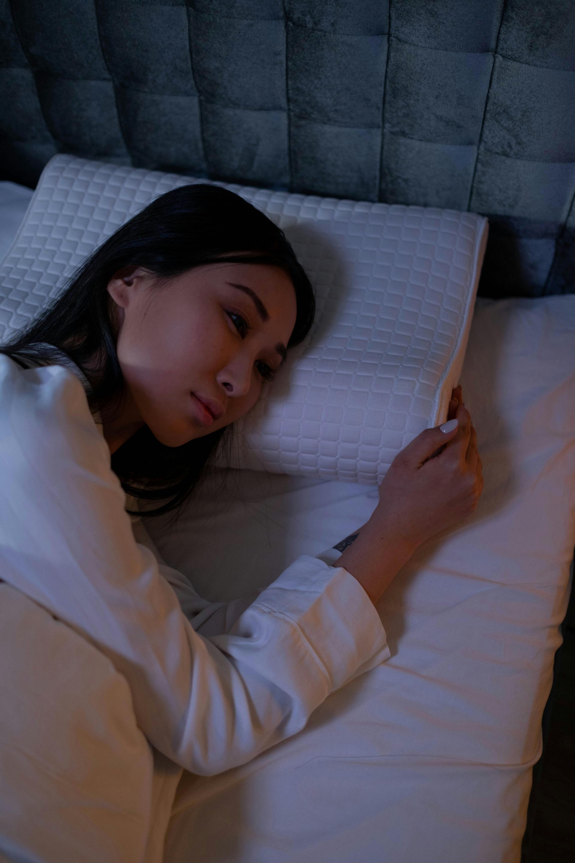 Person awake in bed on a white pillow.