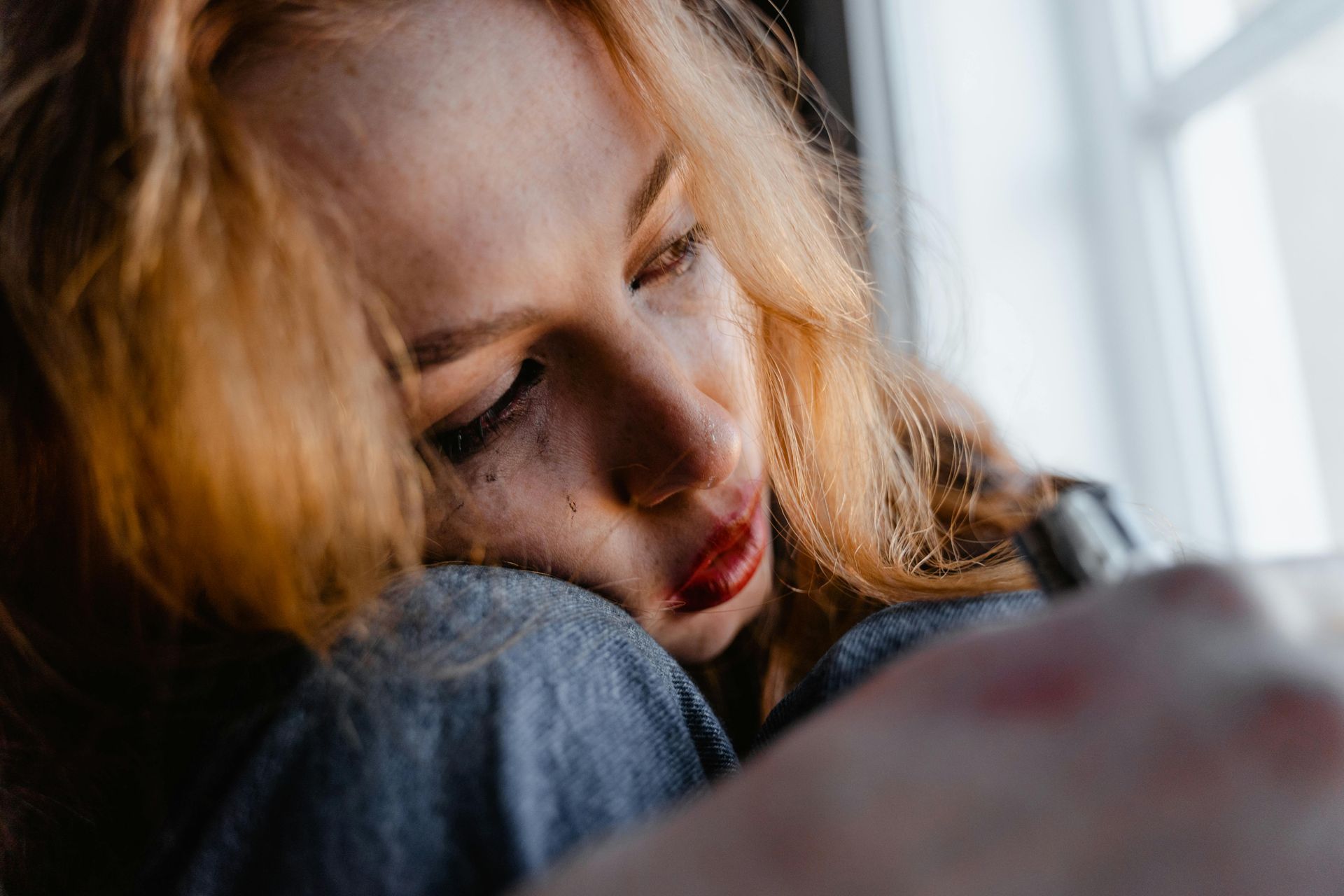 Woman crying and resting near a window.