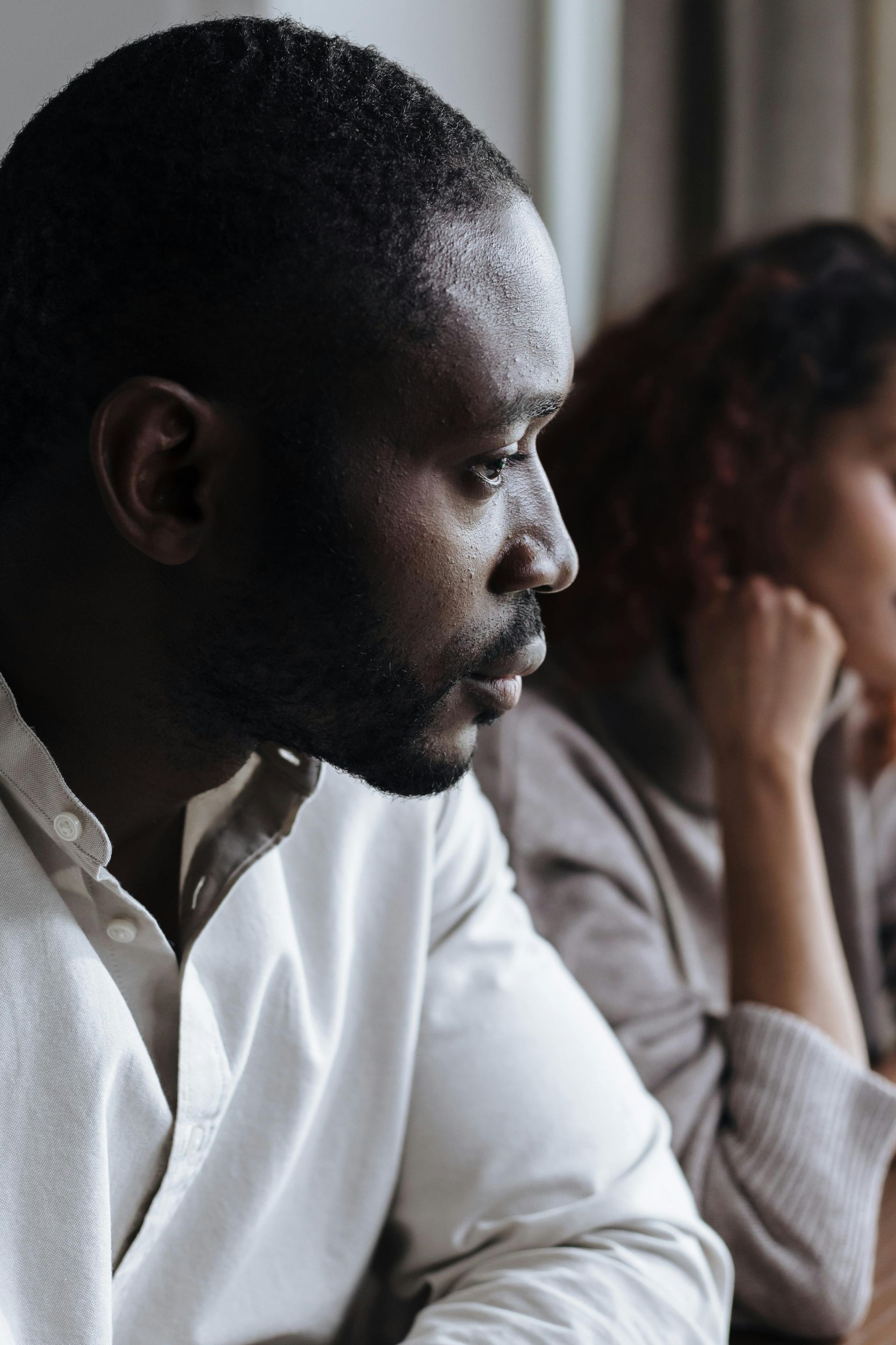 Two people seated indoors, looking out a window in a quiet moment