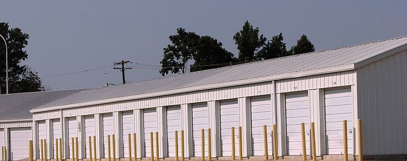White storage units with gray roof under a cloudy sky.