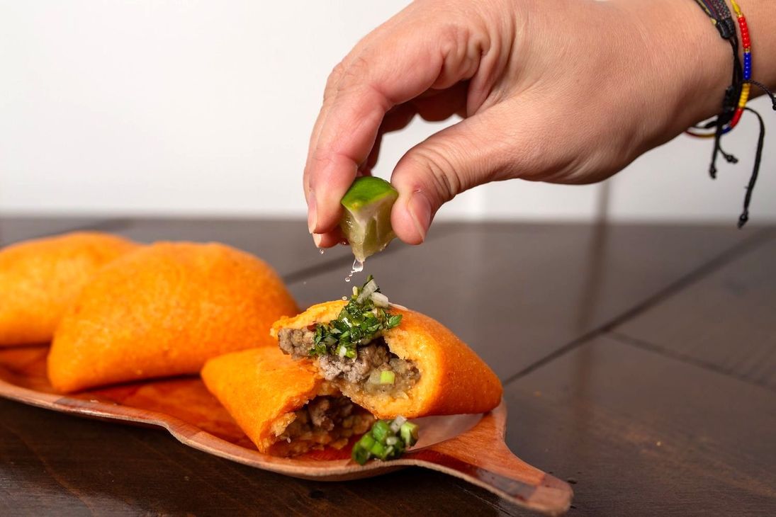 A person is squeezing a lime over a plate of food.