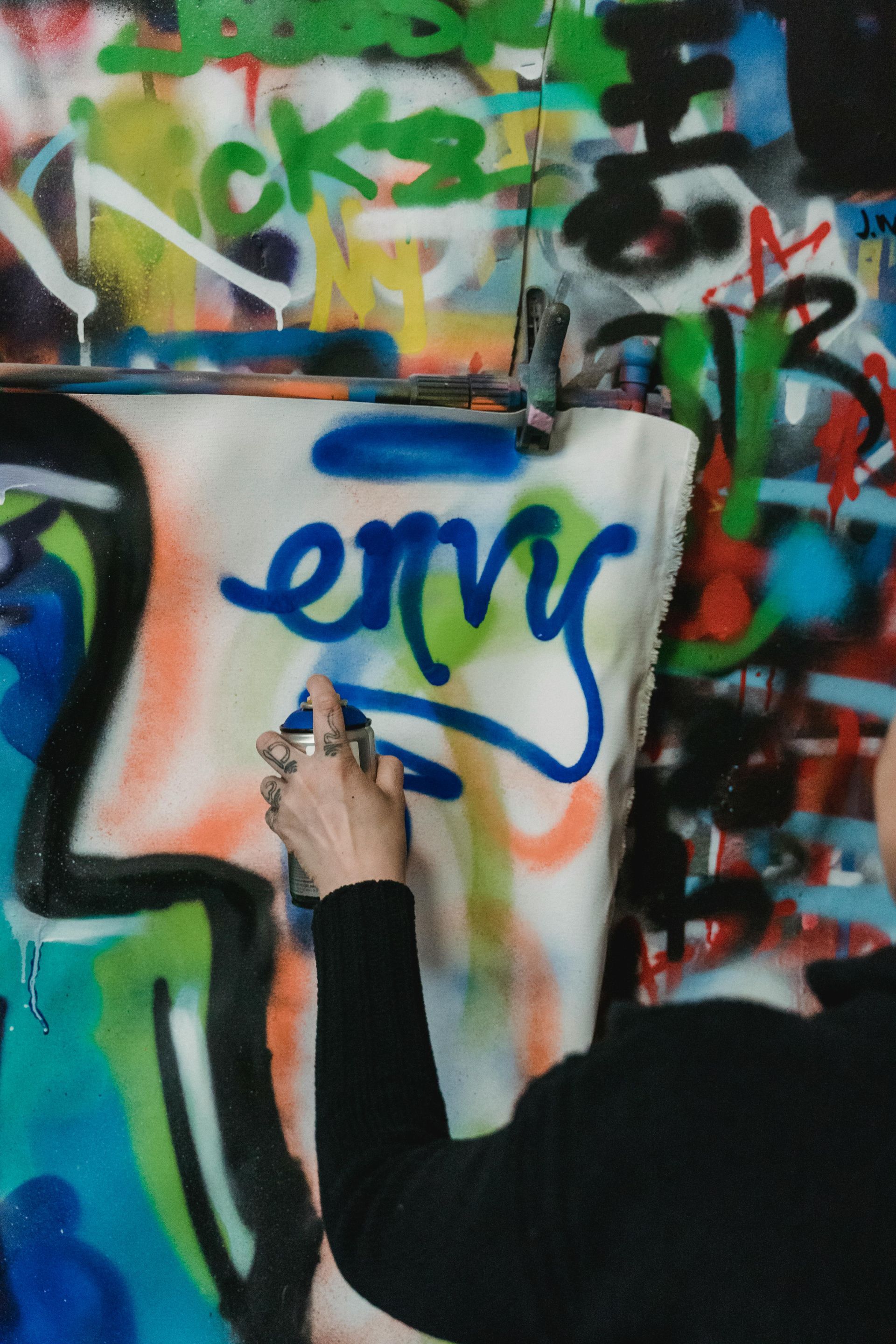 Iemand spuit blauwe verf op een canvas met de graffiti