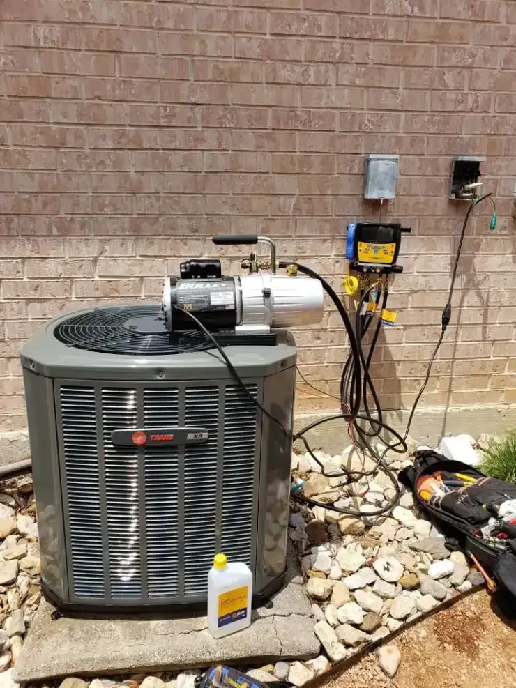 Technician repairing rooftop HVAC unit with gloved hands and tools beside gauges and hoses