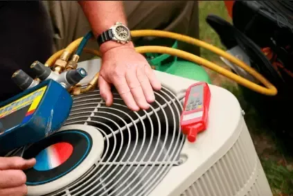 Technician repairing rooftop HVAC unit with gloved hands and tools beside gauges and hoses