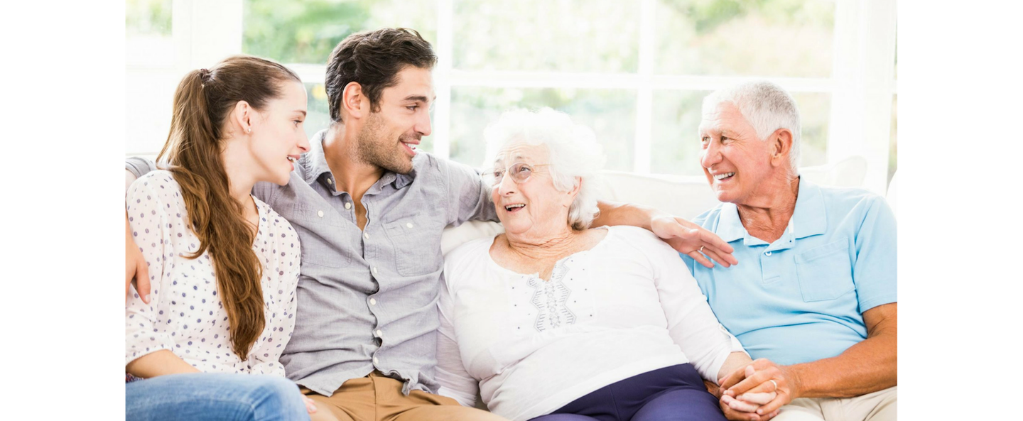 Four people sitting on a couch, smiling and chatting in a bright living room