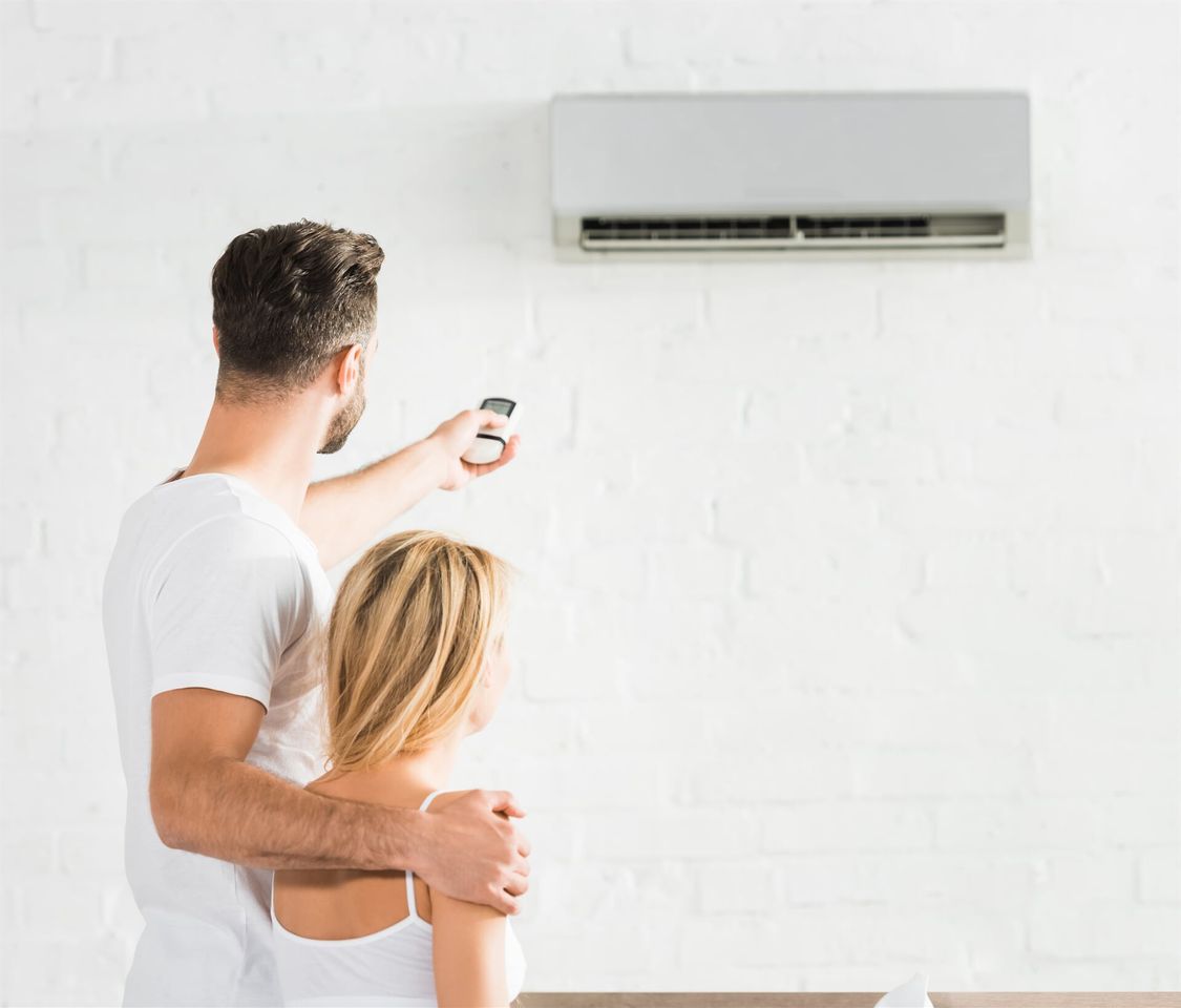A Couple Turning on Their Air Conditioner — Mick’s Air-Conditioning Services in Gracemere, QLD A Couple Turning on Their Air Conditioner — Mick’s Air-Conditioning Services in Gracemere, QLD