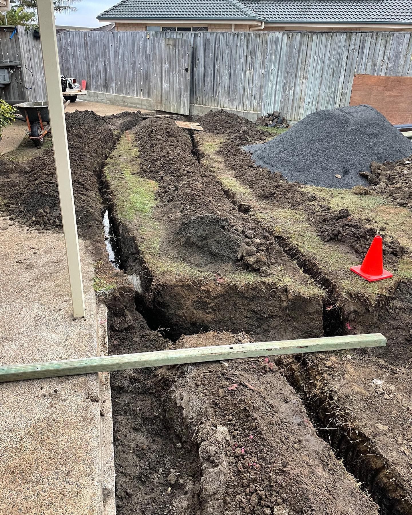 Trenches Dug in a Backyard, Dirt Piles, Orange Cone. Fence in Background — All Access Mini Earthworks in Childers, QLD