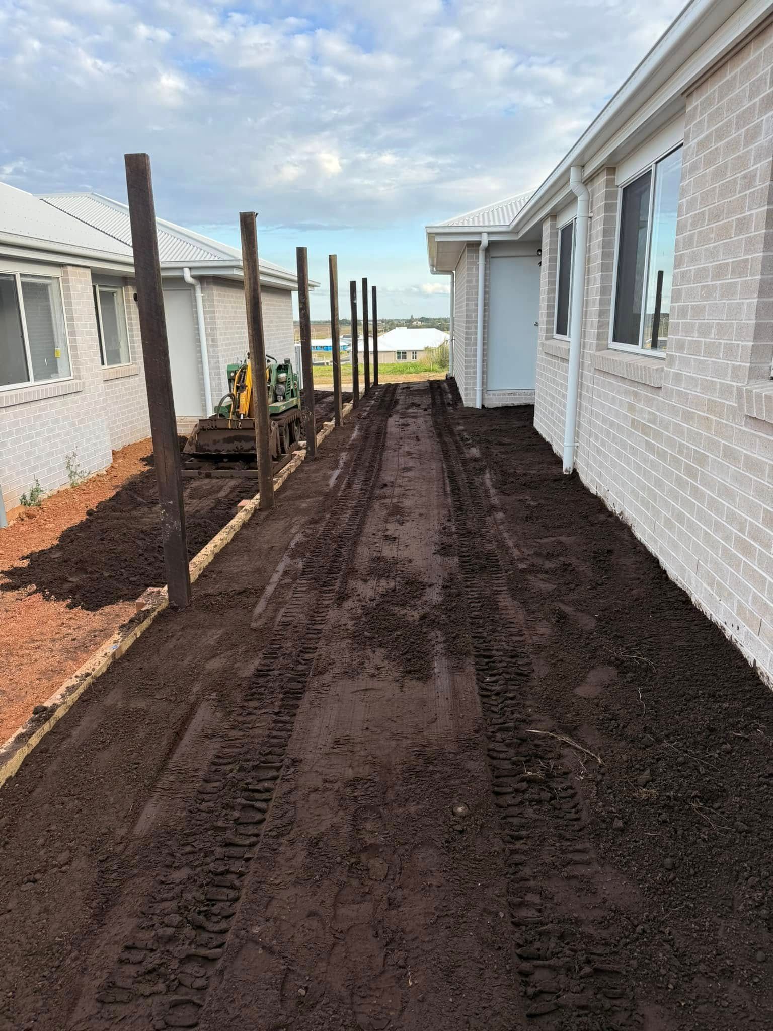 Dirt Path Between Two Houses With Wooden Posts, Tractor Tracks in the Soil — All Access Mini Earthworks in Childers, QLD