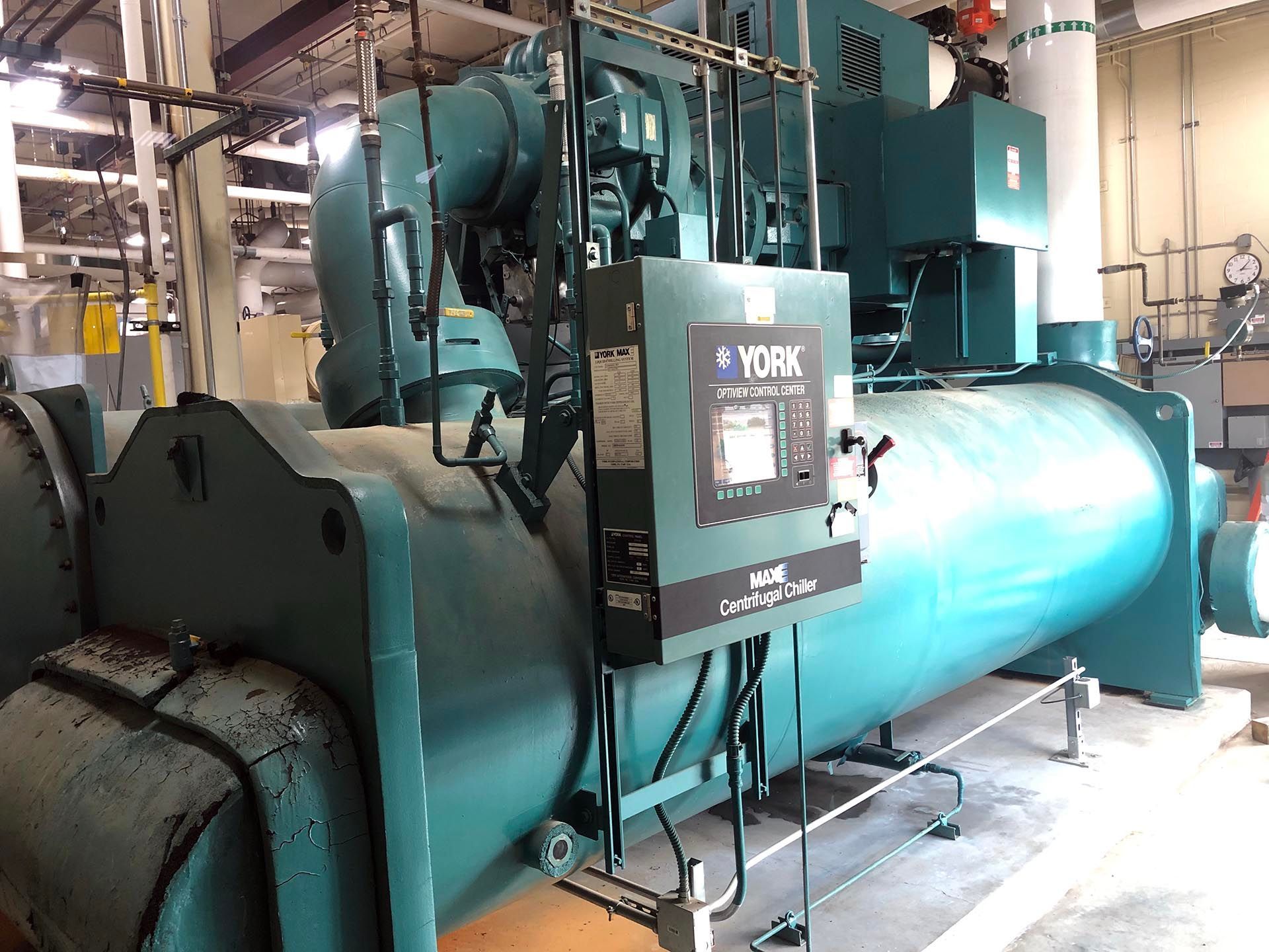A large, teal York chiller in an industrial setting with control panel.