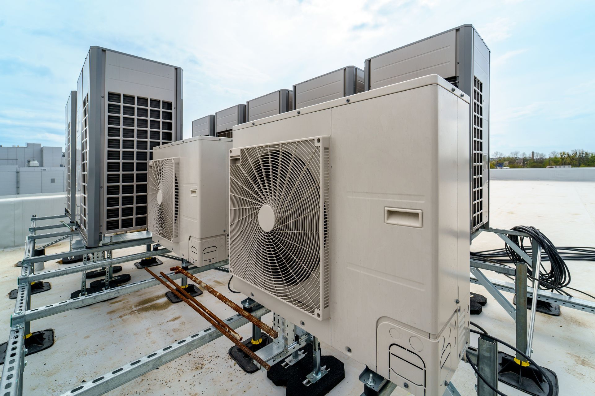 Industrial HVAC units on a rooftop with large fans and metal ductwork against the sky