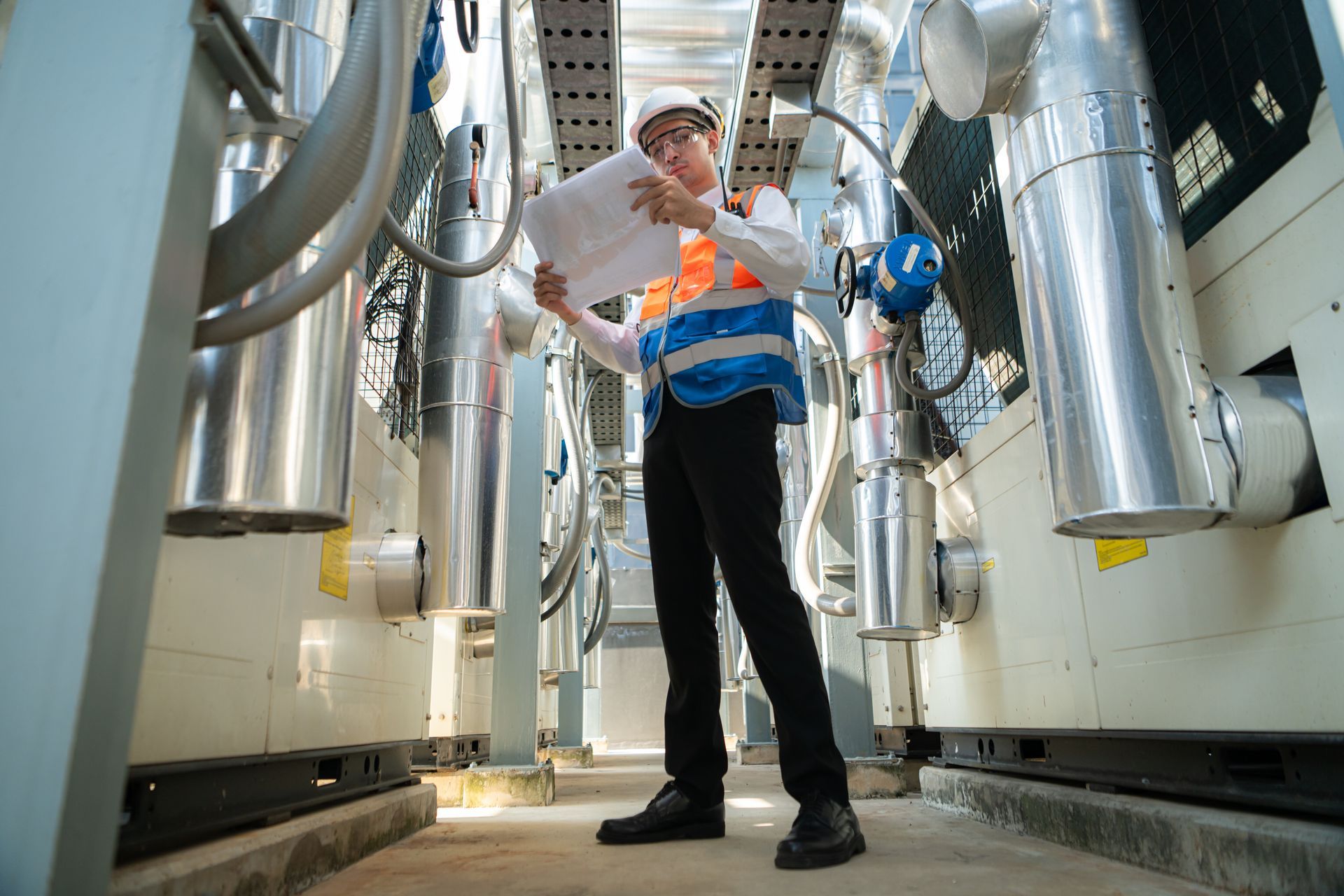 Worker in a hard hat inspecting machinery in a bright industrial facility
