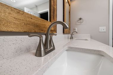 Modern white bathroom sink with speckled countertop and chrome faucet beside a mirror