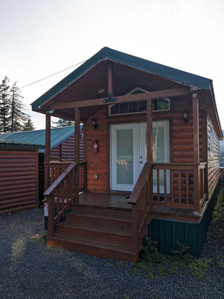 A small log cabin with a porch and stairs