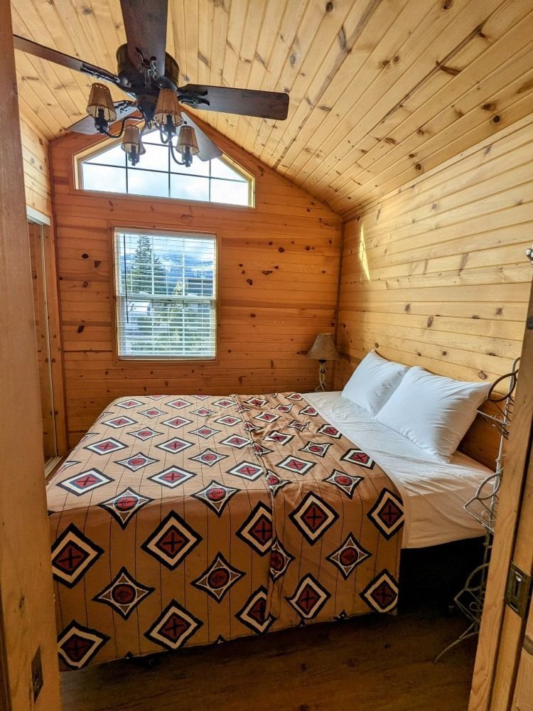 A bedroom with a bed and a ceiling fan