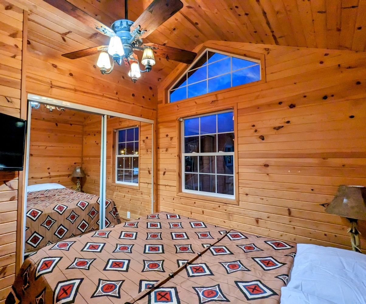 A bedroom in a log cabin with a bed and a ceiling fan.