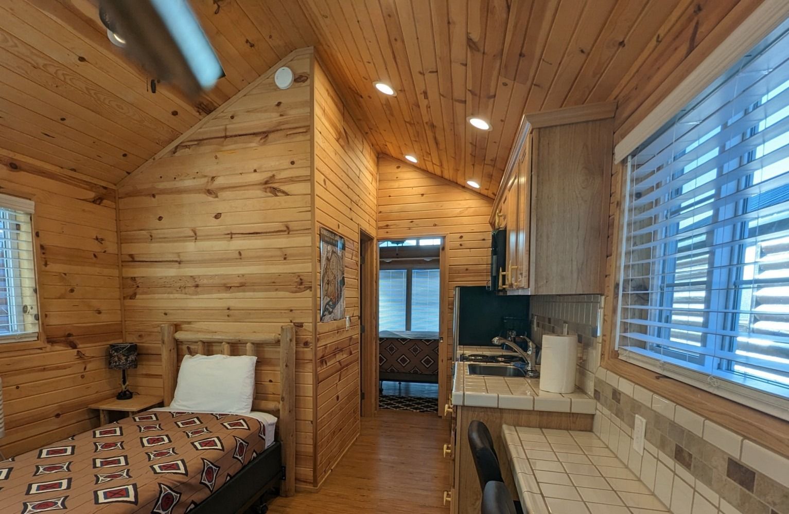 A bedroom in a log cabin with a bed and a kitchen.