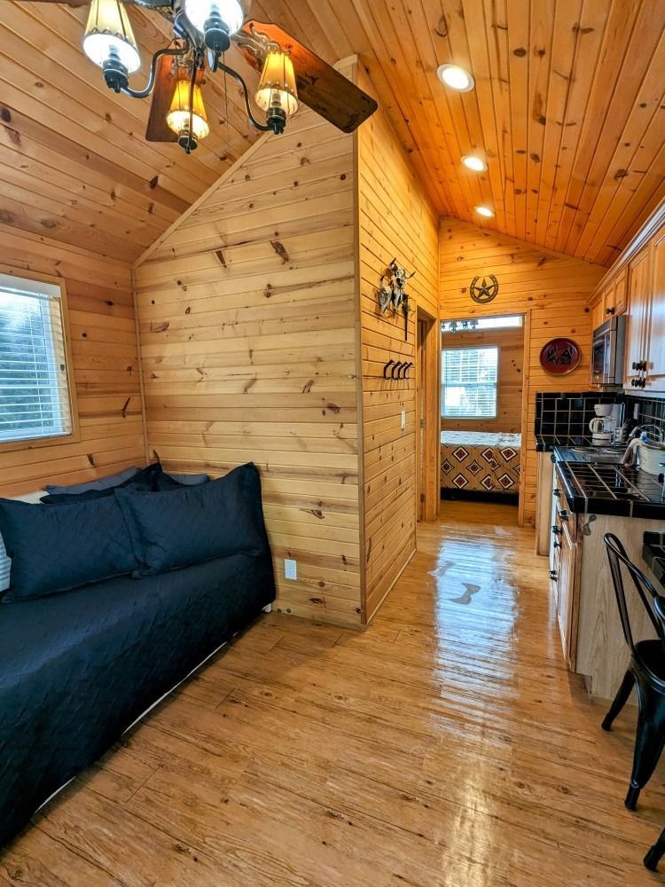 A living room with a couch and a kitchen in a log cabin.