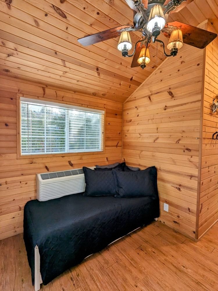 A wooden cabin with a day bed and a ceiling fan.