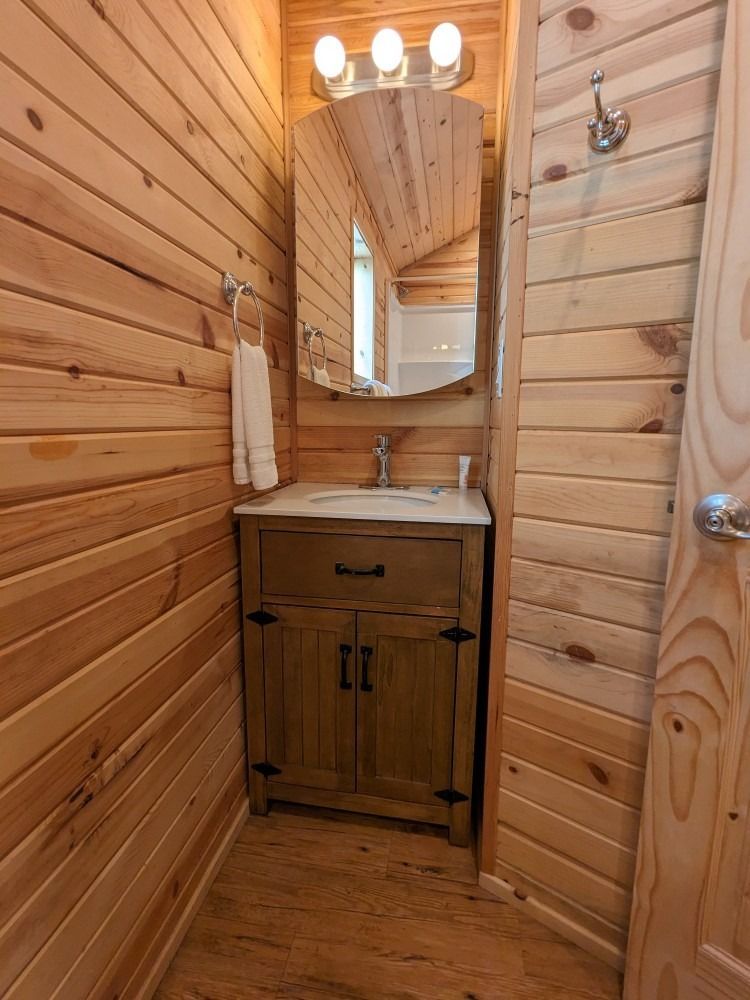 A bathroom with wood paneling and a sink and mirror