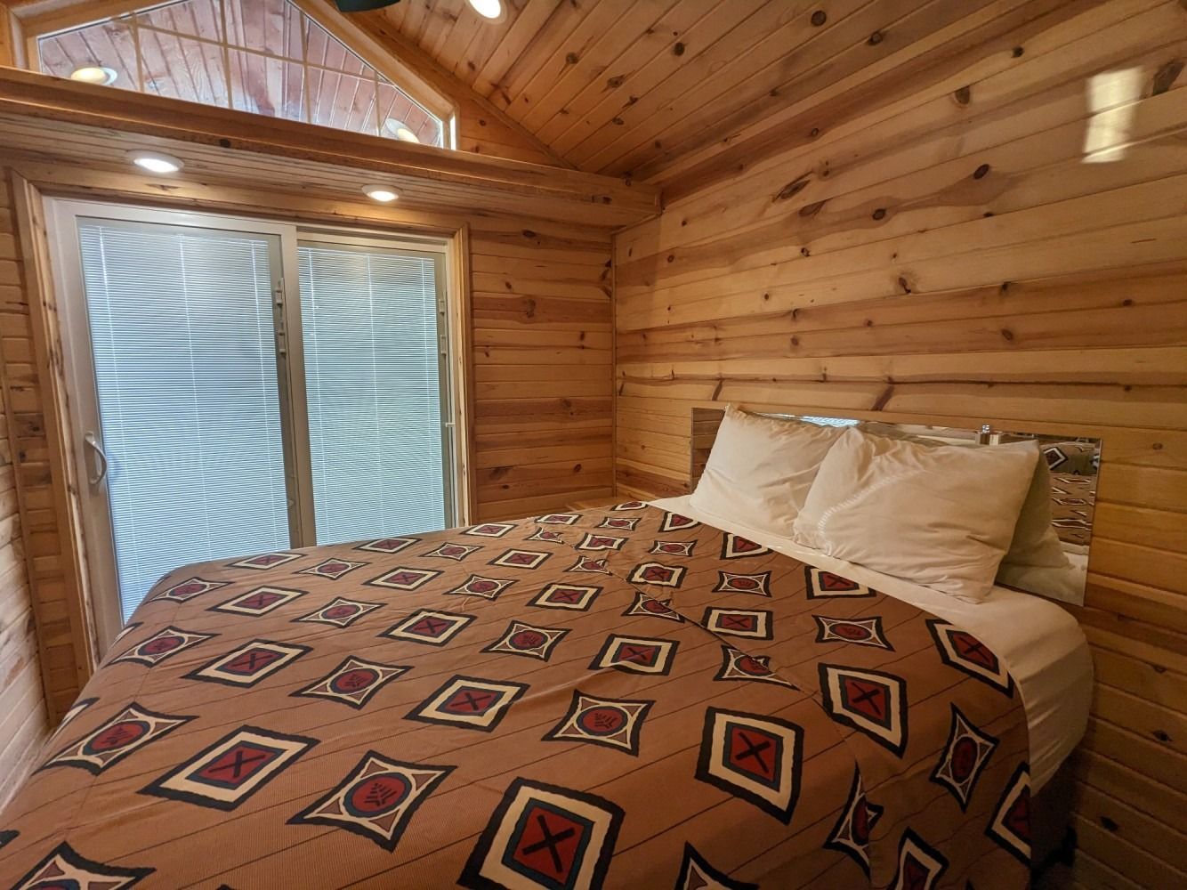 A bedroom in a log cabin with a bed and sliding glass doors.