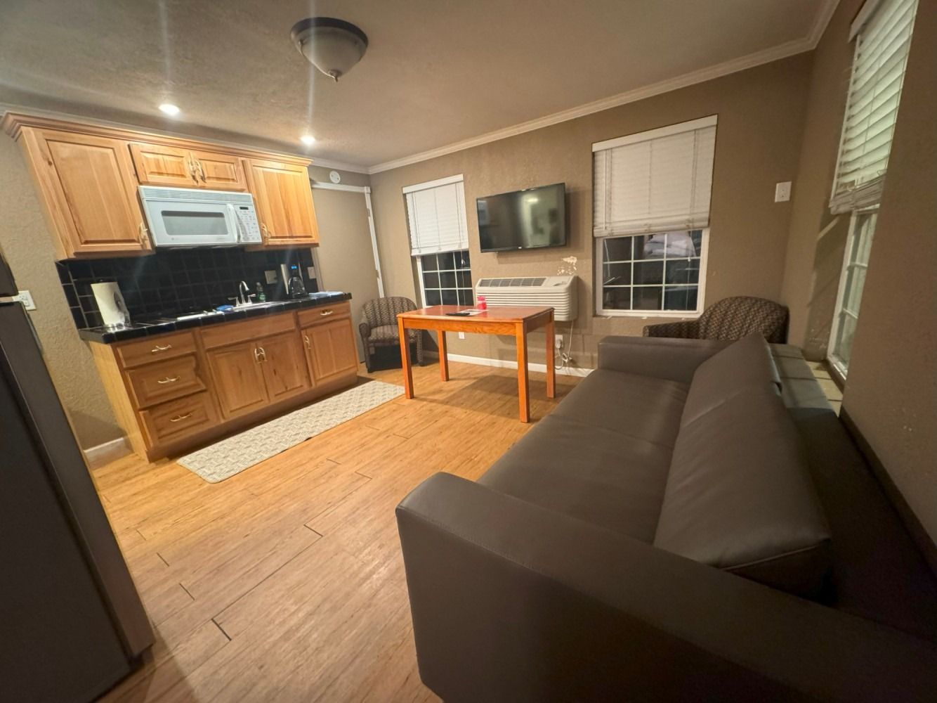 A living room with a couch , table , chairs and a kitchen.