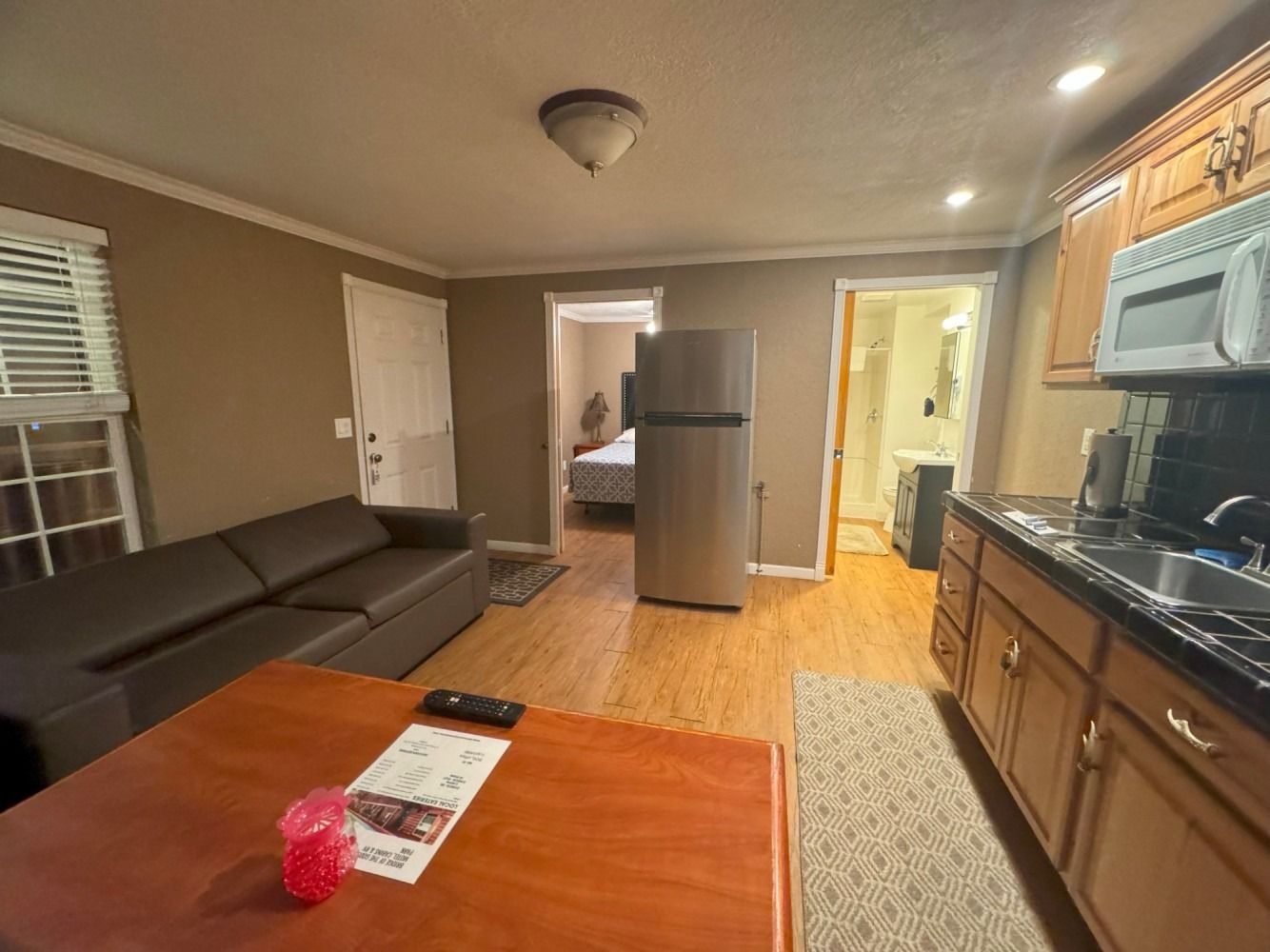 A living room with a couch , table , refrigerator and microwave.