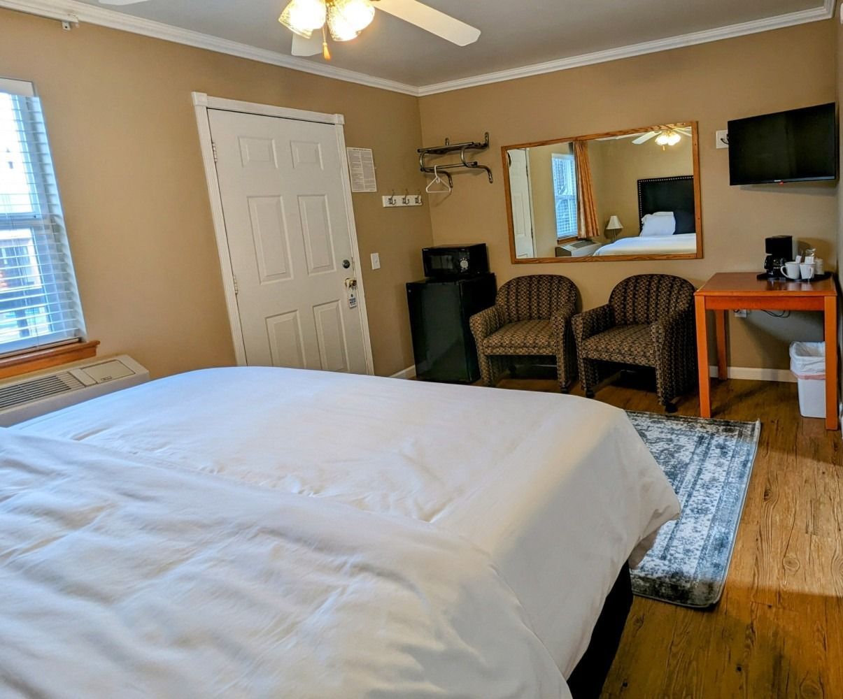 A hotel room with a king size bed , chairs and a television